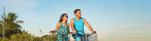 Biking tourists couple cycling enjoying summer outdoor sport activity banner panoramic. Young woman and man riding bicycles on Caribbean vacation. Active people lifestyle happy.