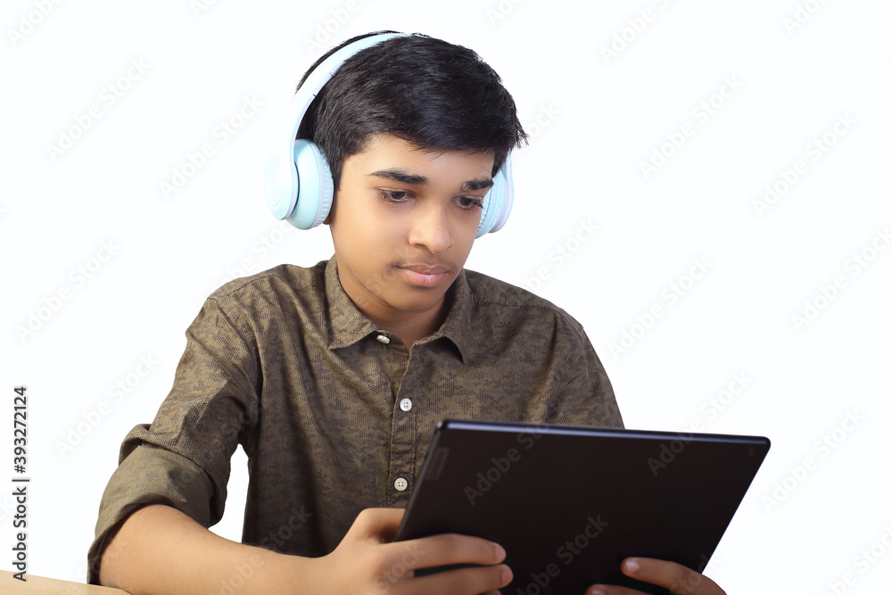 Indian young boy using digital tablet while attending the online classes at home	
