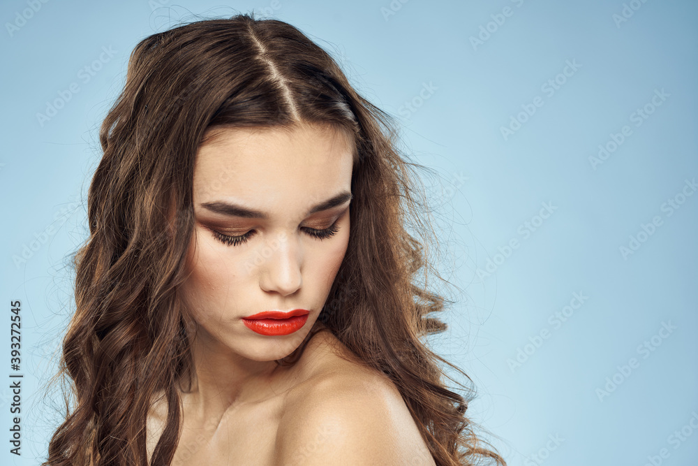 Elegant brunette fashionable hairstyle bright makeup naked shoulders close-up blue background