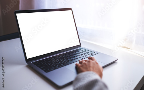 Mockup image of a businesswoman using and touching on laptop computer touchpad with blank white desktop screen on the table