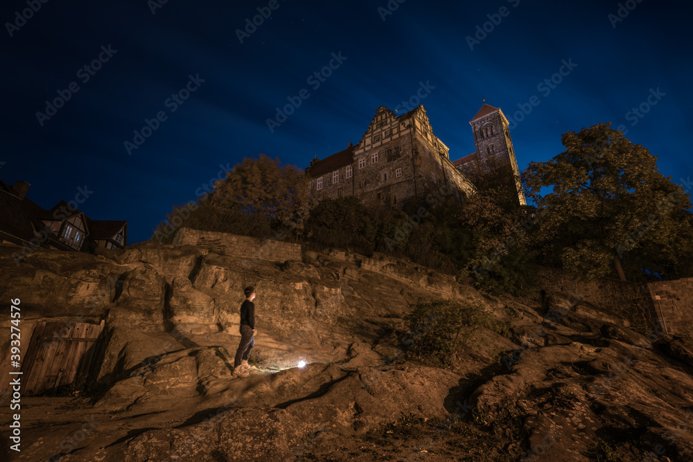 A man stands at the foot of Quedlinburg Castle Hill at night