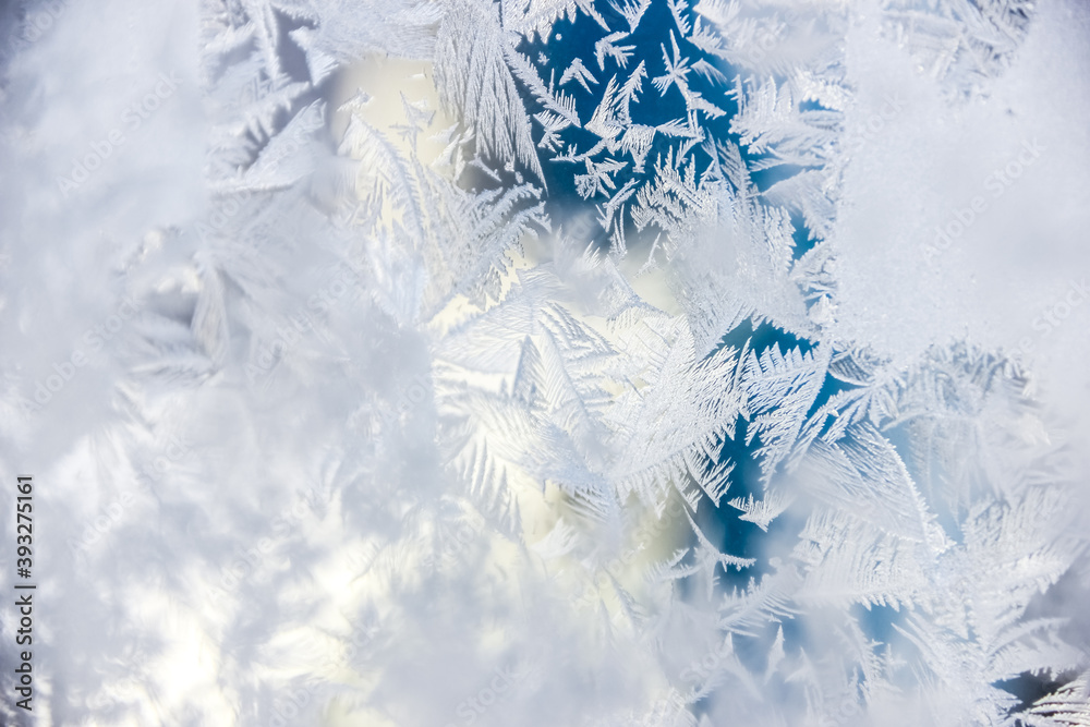 Fototapeta premium Texture of blue frost on a glass window. Frosty cold weather. White ice patterns texture close-up. New year and Christmas background