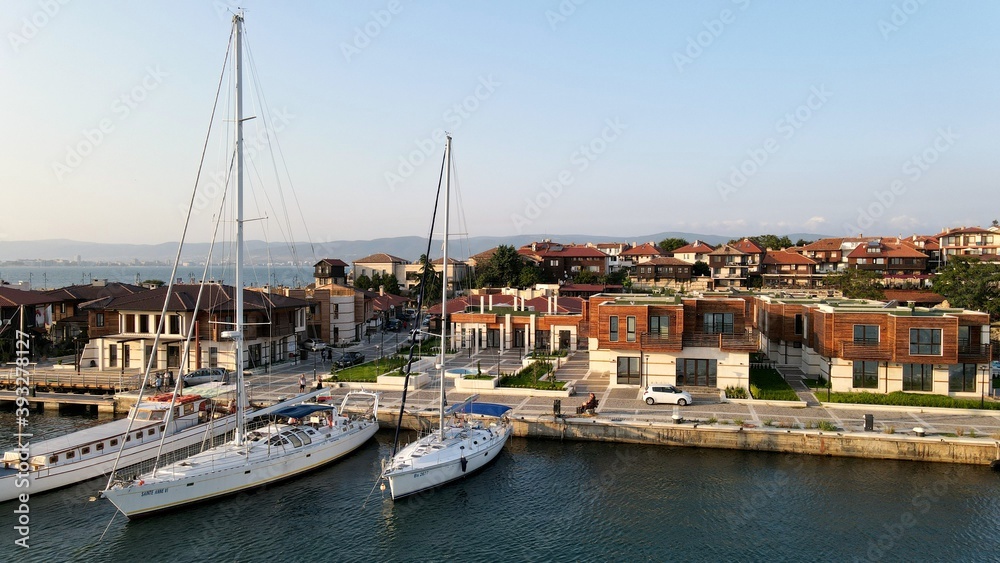 Yachts docked on a small port near modern houses