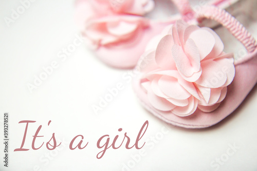 Close-up of pink sandals with a flower for a little girl. First shoes for baby girl on a light background with space for text. Baby shower party. Its a girl