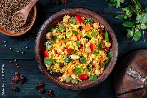 Couscous, overhead flat lay shot in a tagine with ingredients, on a dark wooden background