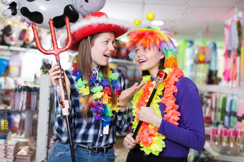 Two cheerful young female friends having fun in festival outfits store while preparing for party