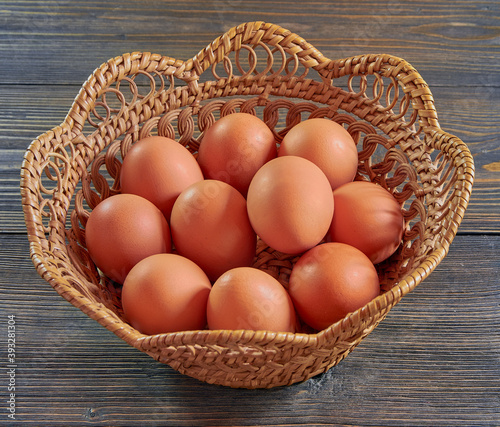 Eggs in a wicker plate on a wooden table, top view. Concept of natural farm products.