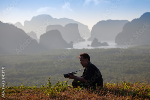 .A photographer prepares a camera for taking pictures of beautiful scenery in the morning.. © Narong Niemhom