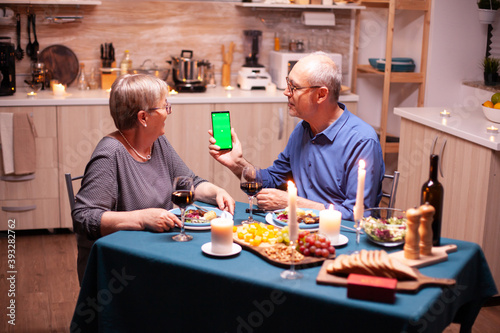Old senior retired couple holding green screen
