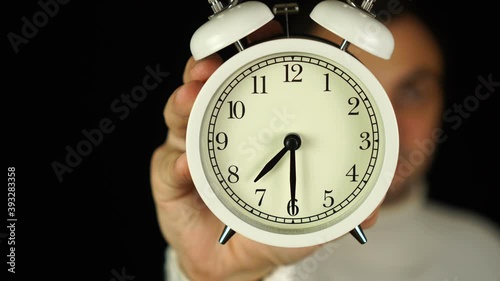 7:30 o'clock. Human hand holding alarm clock that showing seven-thirty o'clock and ringing.
