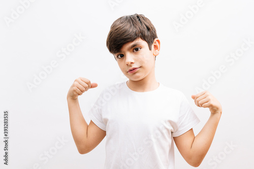 Little boy hispanic kid wearing casual white tshirt very happy and excited doing winner gesture with arms raised, smiling and screaming for success. celebration concept.