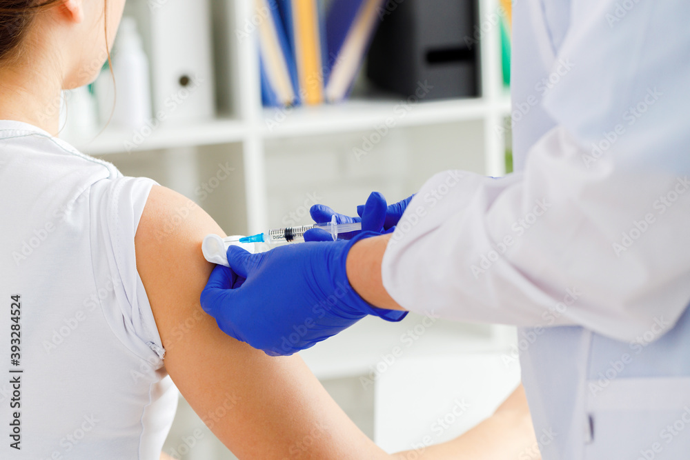 Doctor hands making a vaccination in the shoulder of patient Doctor hands making a vaccination in the shoulder of patient