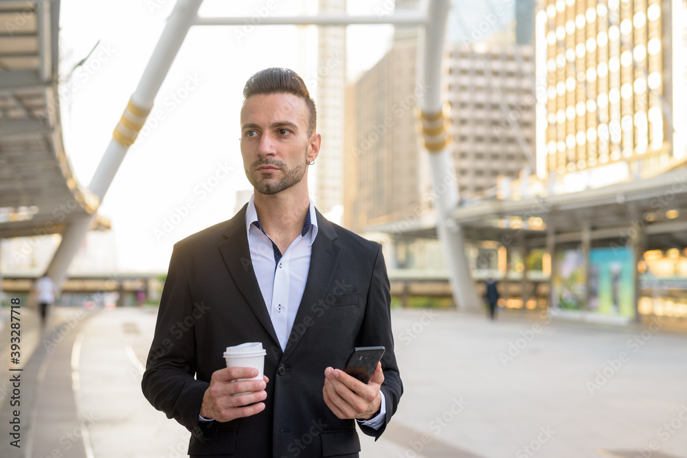 Businessman outdoors holding coffee cup and mobile phone Businessman outdoors holding coffee cup and mobile phone