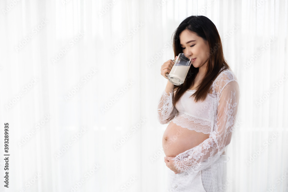 pregnant woman drinking a milk at the window in bedroom pregnant woman drinking a milk at the window in bedroom