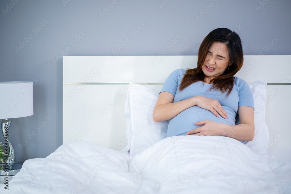 pregnant woman has a stomachache on bed pregnant woman has a stomachache on bed