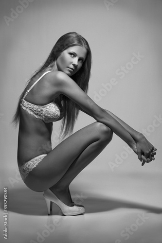beautiful slender blonde girl in light lingerie posing in the studio