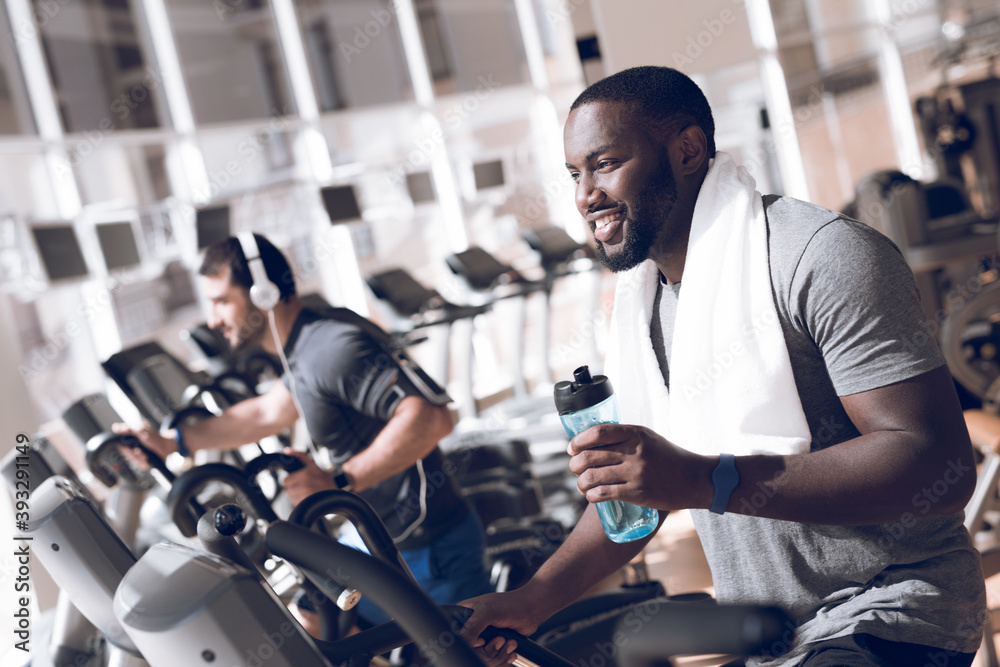 Two men are engaged on treadmills in modern gym. Two men are engaged on treadmills in modern gym.