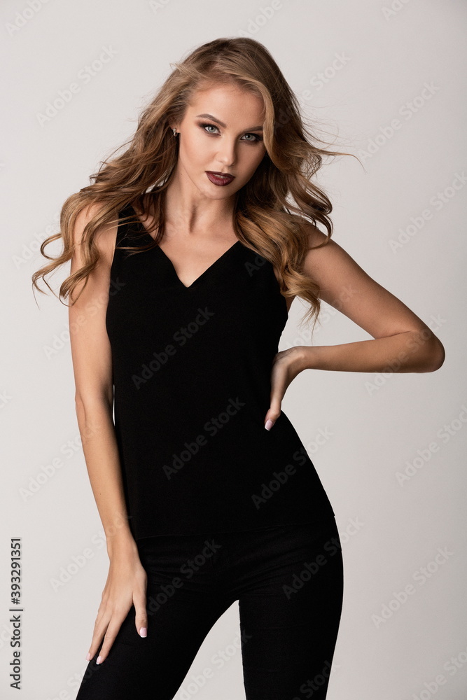 beautiful slender blonde girl in black pants and a T-shirt on a white background beautiful slender blonde girl in black pants and a T-shirt on a white background