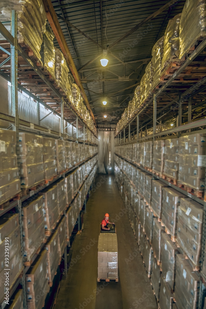 Warehouse worker going among the shelves in a warehouse Warehouse worker going among the shelves in a warehouse