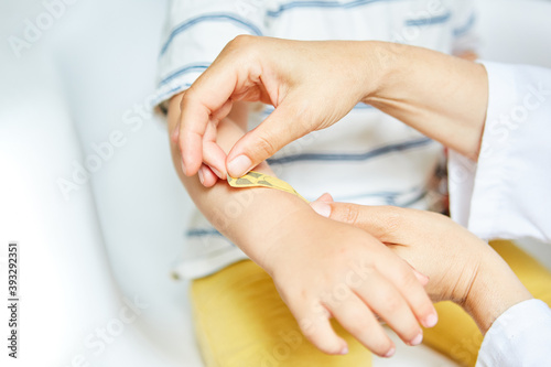 Pediatrician sticks a plaster on hand with bruise
