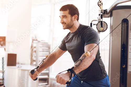 A man is doing strength exercises in gym. 