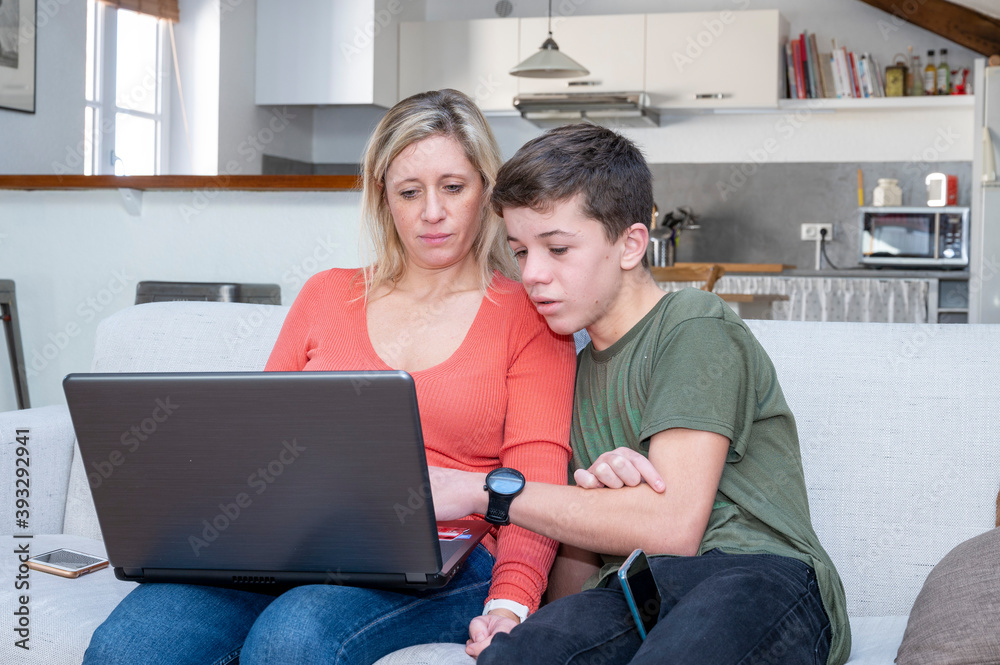 Obraz premium Adolescent et sa mère assis ensemble devant l'écran d'un ordinateur portable