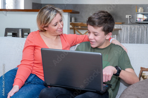 Adolescent et sa mère assis ensemble devant l'écran d'un ordinateur portable