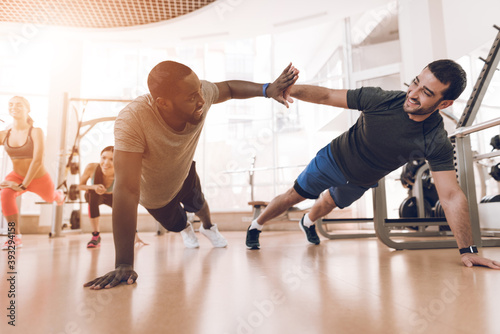 Two men squeeze off the floor in a modern gym.