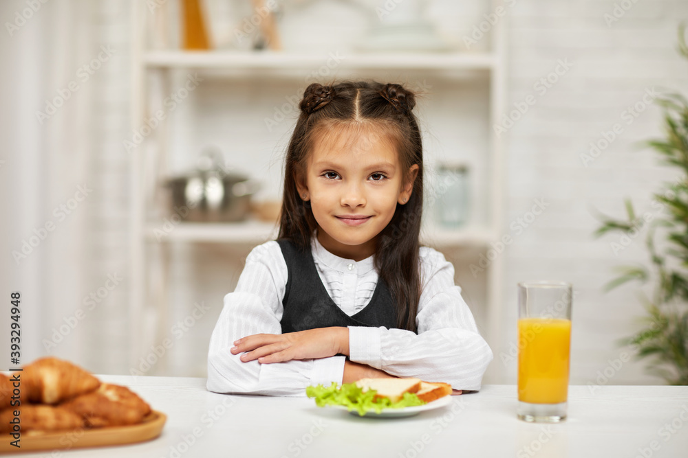 little child girl in school uniform having breakfast - sandwich and orange juice in the kitchen. healthy breakfast little child girl in school uniform having breakfast - sandwich and orange juice in the kitchen. healthy breakfast