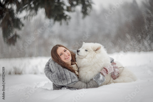 Fototapeta Naklejka Na Ścianę i Meble -  Beautiful woman with dog samoyed in winter forest