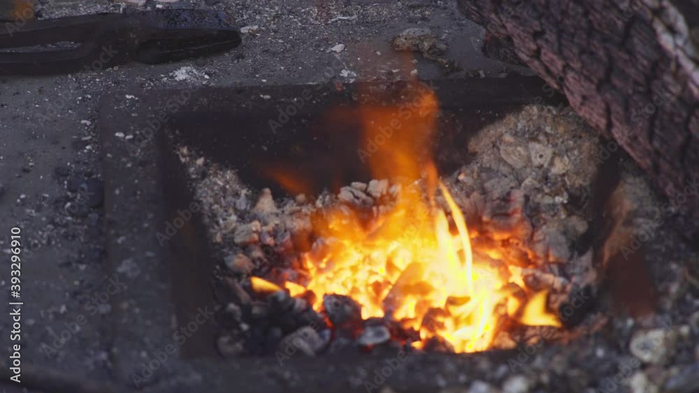 Close-up shot burning fire in the hot furnace of the forge. Dark workshop of a blacksmith with an anvil, tools and a stove on street easter fair in Prague Close-up shot burning fire in the hot furnace of the forge. Dark workshop of a blacksmith with an anvil, tools and a stove on street easter fair in Prague