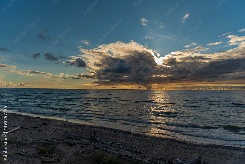 Obraz premium sunset behind the clouds close to the water horizon