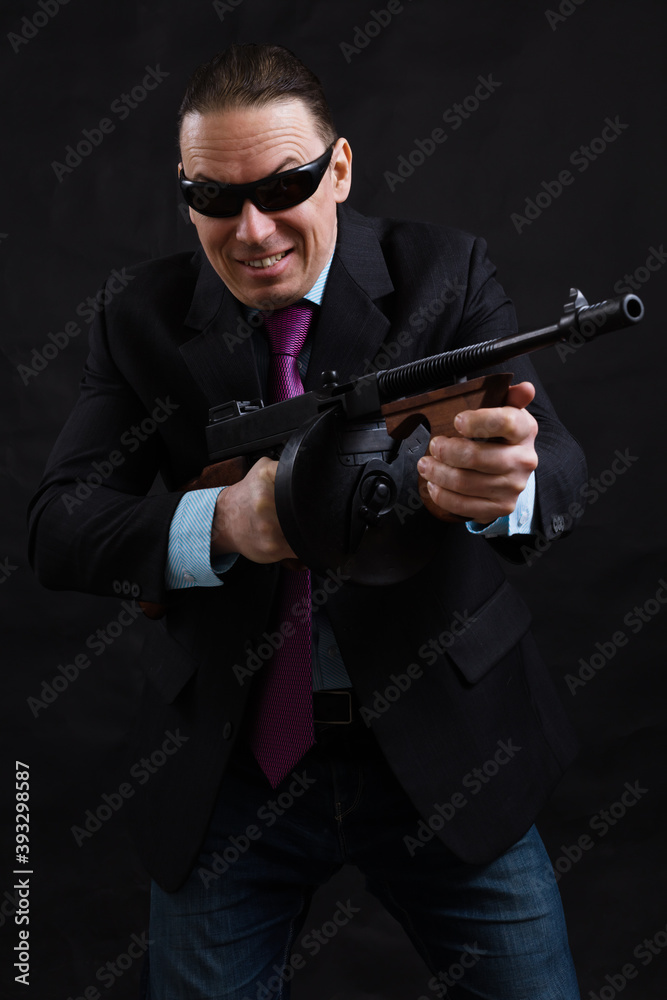 Mature gangster in sunglasses dressed in suit with tommy gun Mature gangster in sunglasses dressed in suit with tommy gun