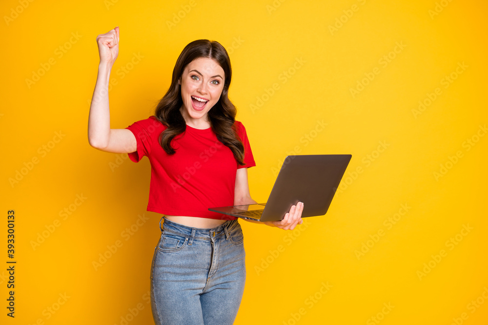 Photo of delighted girl work laptop win raise fists scream wear red t-shirt isolated bright shine color background Photo of delighted girl work laptop win raise fists scream wear red t-shirt isolated bright shine color background