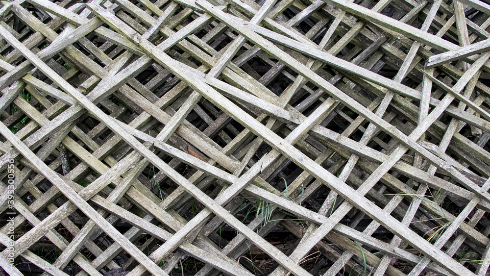Old gray diagonal wooden grate. Old fence made of wooden lattices. Background Old gray diagonal wooden grate. Old fence made of wooden lattices. Background