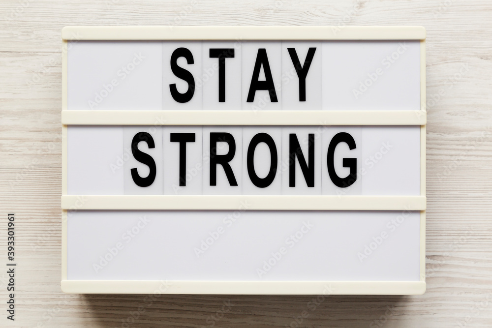 'Stay strong' on a lightbox on a white wooden background, top view. Flat lay, overhead, from above.