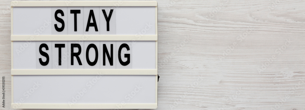 'Stay strong' on a lightbox on a white wooden surface, top view. Flat lay, overhead, from above. Space for text. 'Stay strong' on a lightbox on a white wooden surface, top view. Flat lay, overhead, from above. Space for text.