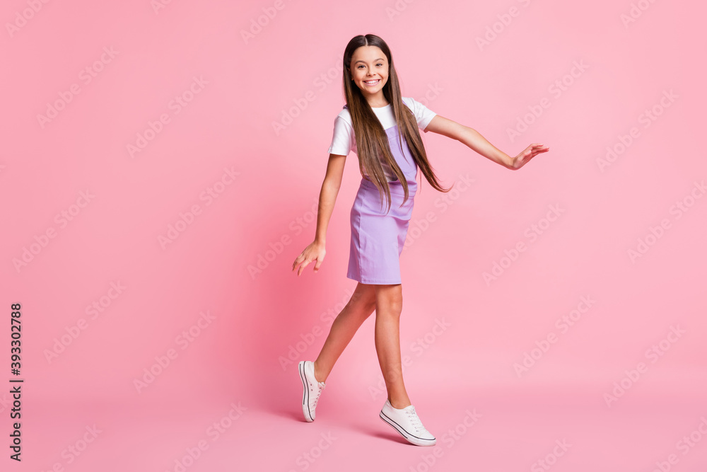 Full body photo of pretty girl walk with toothy smile wear purple overall isolated over pink color background Full body photo of pretty girl walk with toothy smile wear purple overall isolated over pink color background