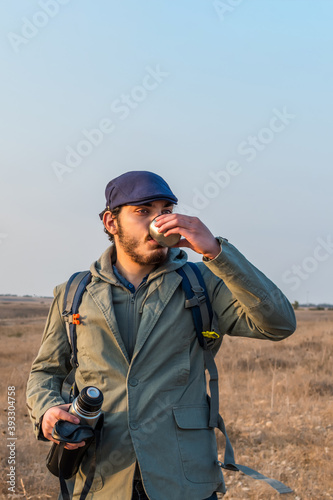 The man hiker drink a cup of hot coffee. Winter adventure.