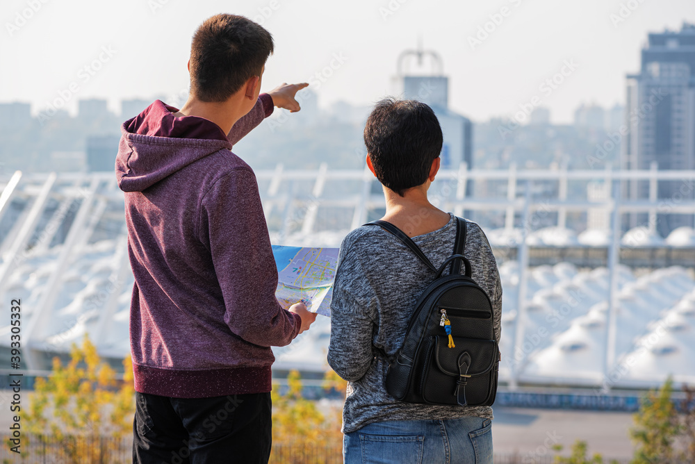 Happy mother and son standing at observation deck and looking on the city enjoying spending time together on vacations. Rear view.