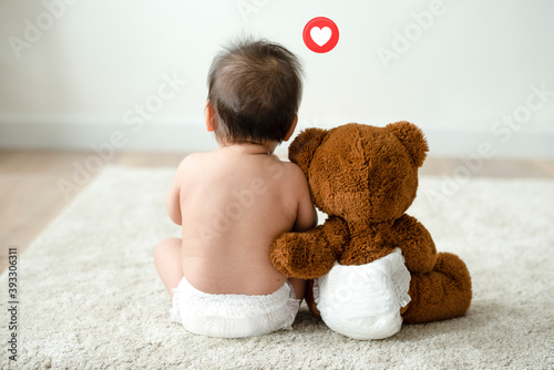 Toddler sitting beside his teddy bear