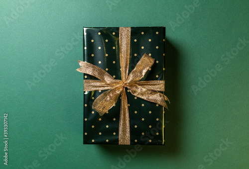 one Christmas wrapped gift on green background photo