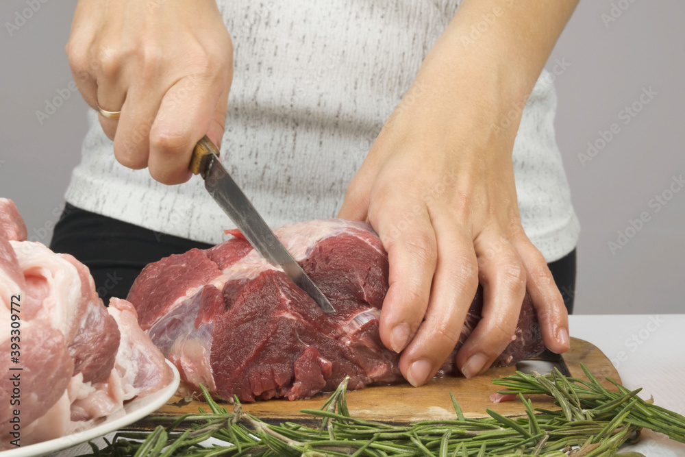 women's hands cut pieces of beautiful red meat with a knife. Cooking meat steaks, chops. pieces of beef meat.