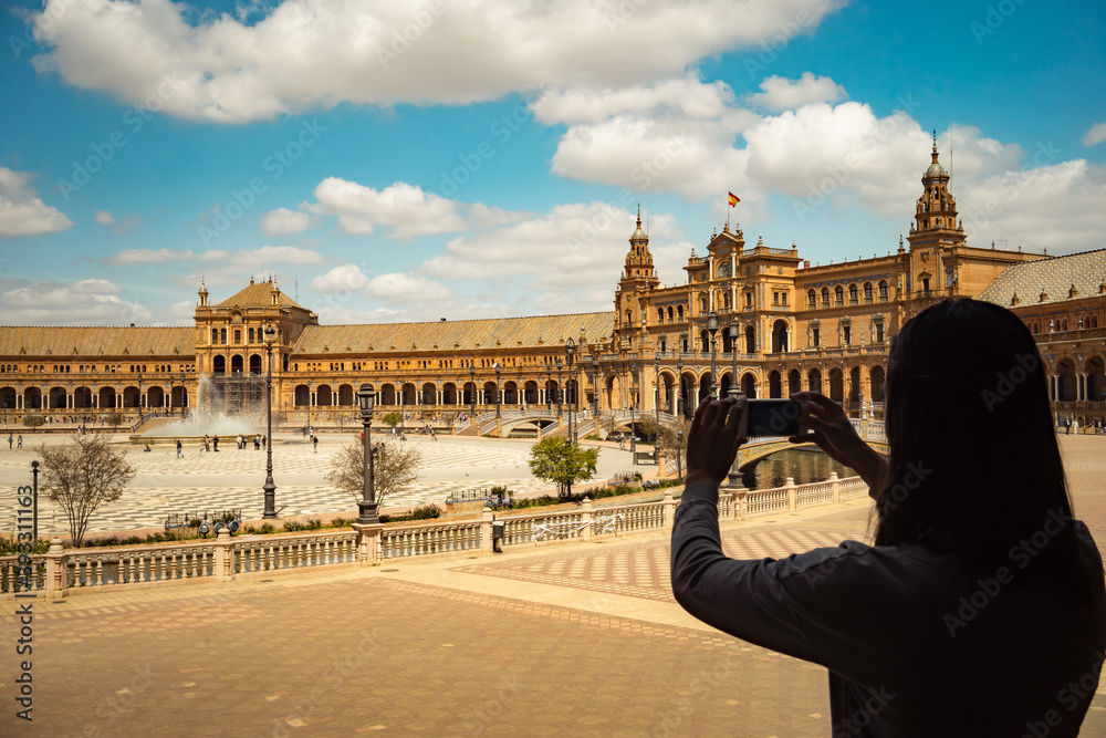 Sevilla Plaza de Espana bridge Andalusia Spain Girl making photo of famous historic touristic place at her travel. Backpack travel concept.