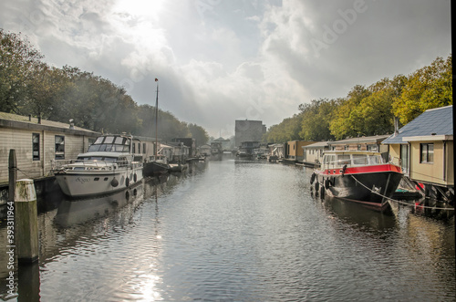 Schiedam, the Netherlands, October 23, 2020: houseboats, sloops and small yachts in Westerhaven canal under a dramatic sky photo