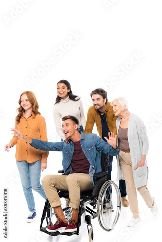 Smiling multiethnic friends walking near man in wheelchair on white background