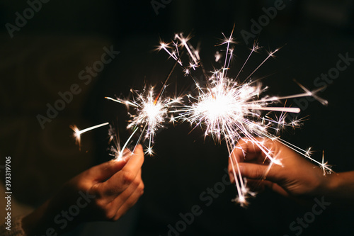 Burning New Year sparkler. Bengal light scattering into small sparkles. Celebrating christmas and new year 2021