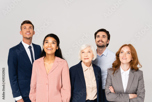 Smiling multicultural businesspeople looking up isolated on grey