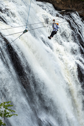 A person rides on a zipline over Montmorency falls