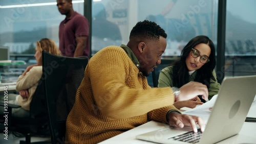 Ethnic male working with female colleague typing on laptop doing business in office